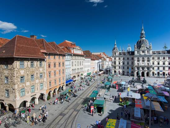 View from above on the main square of Graz. People bustle around the square.